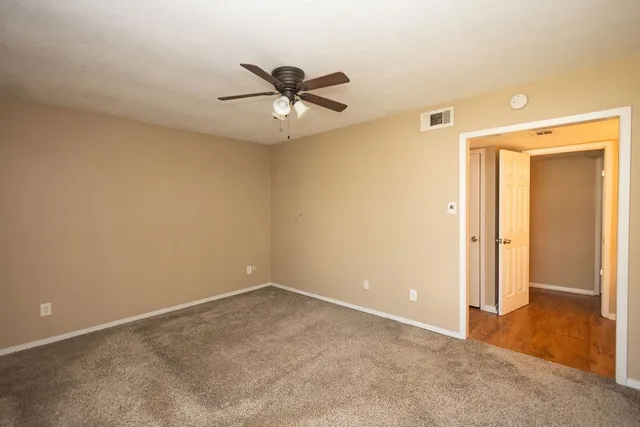 an empty room with closet and a chandelier fan