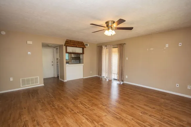 a view of an empty room with window and wooden floor