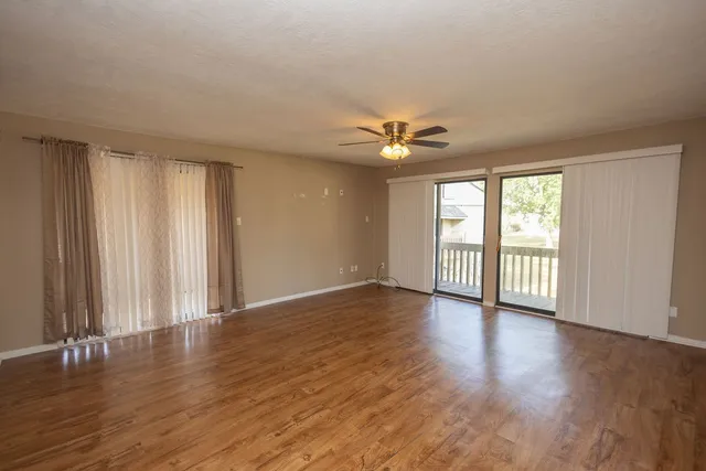 an empty room with wooden floor and windows