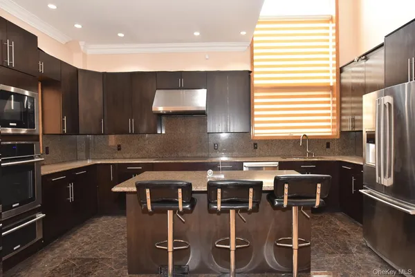 a kitchen with stainless steel appliances granite countertop a stove a sink a microwave a refrigerator and island