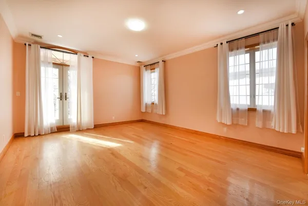 a view of an empty room with a window and wooden floor