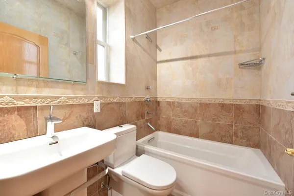 a bathroom with a sink a toilet a mirror and bathtub
