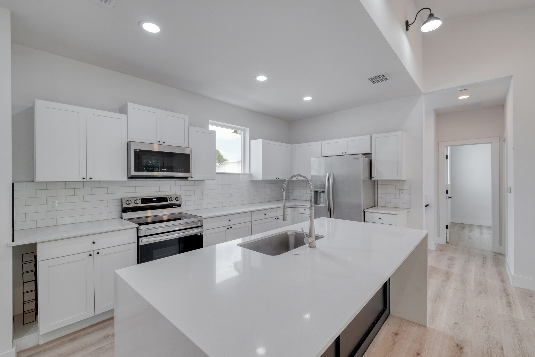5211 Rob-Scott Street Austin, TX 78721 - Photo 8 of 24 A sleek, contemporary kitchen with white cabinetry, a spacious island, and stainless steel appliances.