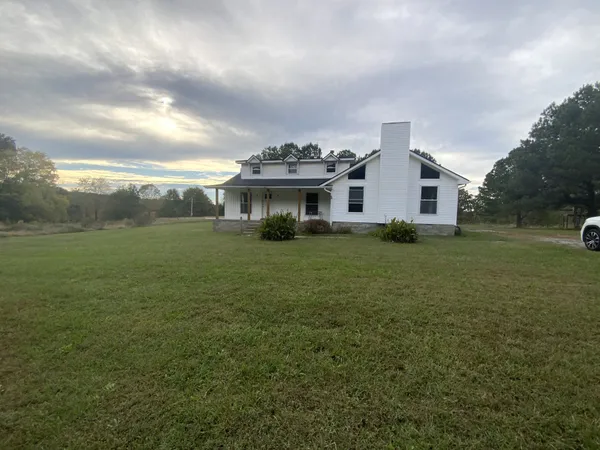 a view of a house with a big yard and large trees
