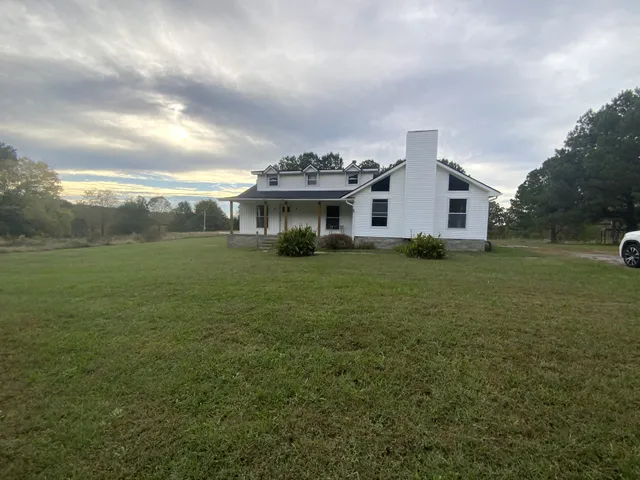 a view of a house with a big yard and large trees