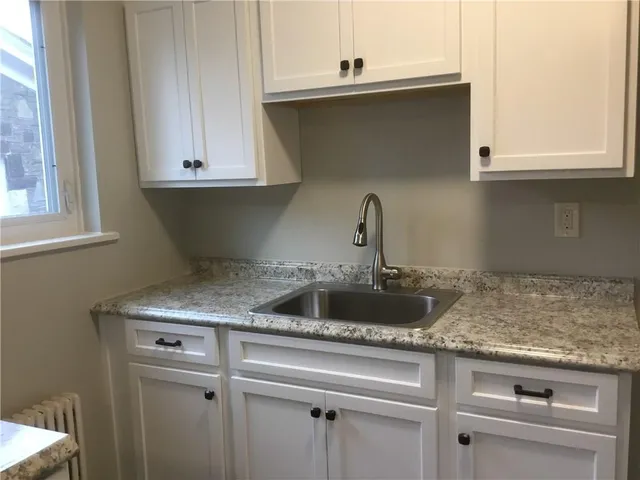 an empty room with wooden floor cabinet and windows
