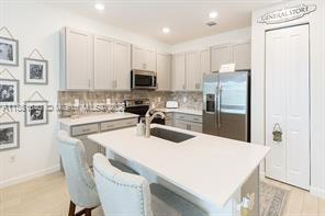 14531 Bretton Woods Trace Delray Beach, FL 33446 - Photo 3 of 57 a kitchen with stainless steel appliances a refrigerator a stove a sink a dining table and chairs
