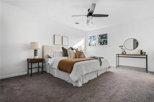 a spacious bedroom with a bed a dresser and potted plant