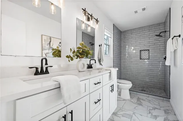 a bathroom with a double vanity sink toilet and shower