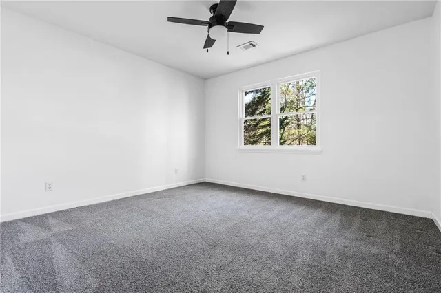 an empty room with windows and ceiling fan