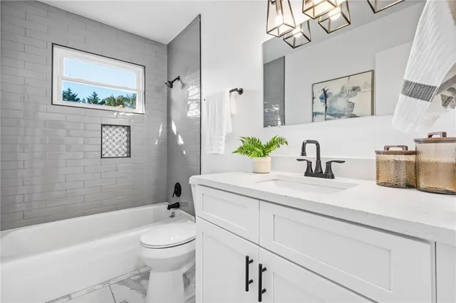 a bathroom with a granite countertop sink a toilet a mirror a vanity a bath tub and shower