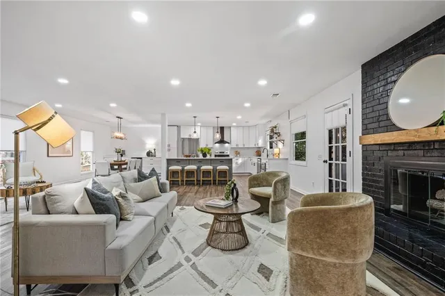 a living room with couches a fireplace kitchen view and a fireplace