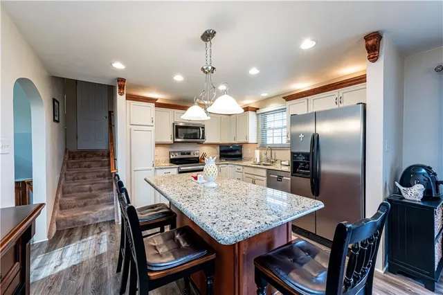 a kitchen with stainless steel appliances granite countertop a refrigerator a sink a stove and cabinets
