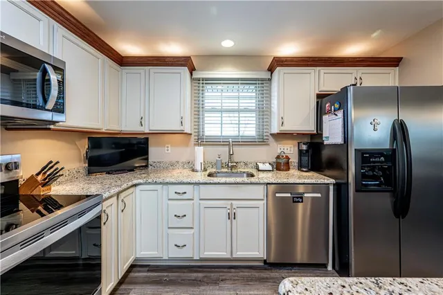 a kitchen with granite countertop a sink a stove top oven and cabinetry