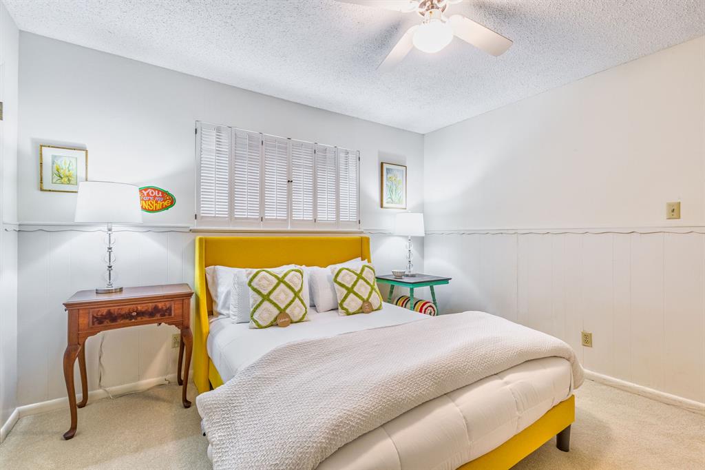 Bedroom featuring a textured ceiling, carpet, ceiling fan, and a wainscoted wall