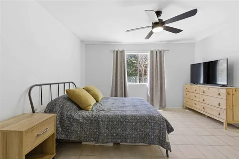 a bedroom with a bed a flat screen tv and a window