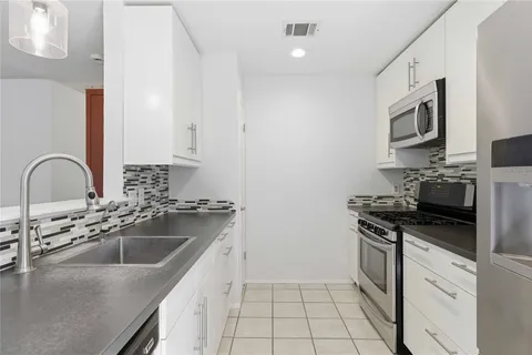 a kitchen with stainless steel appliances granite countertop a sink stove top oven and refrigerator