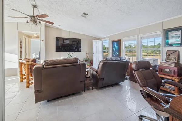 a large living room with stainless steel appliances granite countertop furniture a fireplace a flat screen tv and a large window