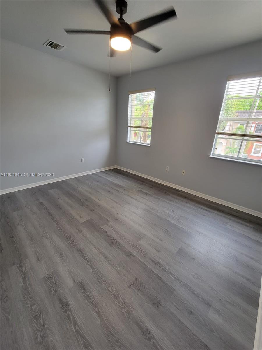 751 Southeast 2nd Street Homestead, FL 33030 - Photo 16 of 18 an empty room with wooden floor chandelier fan and windows