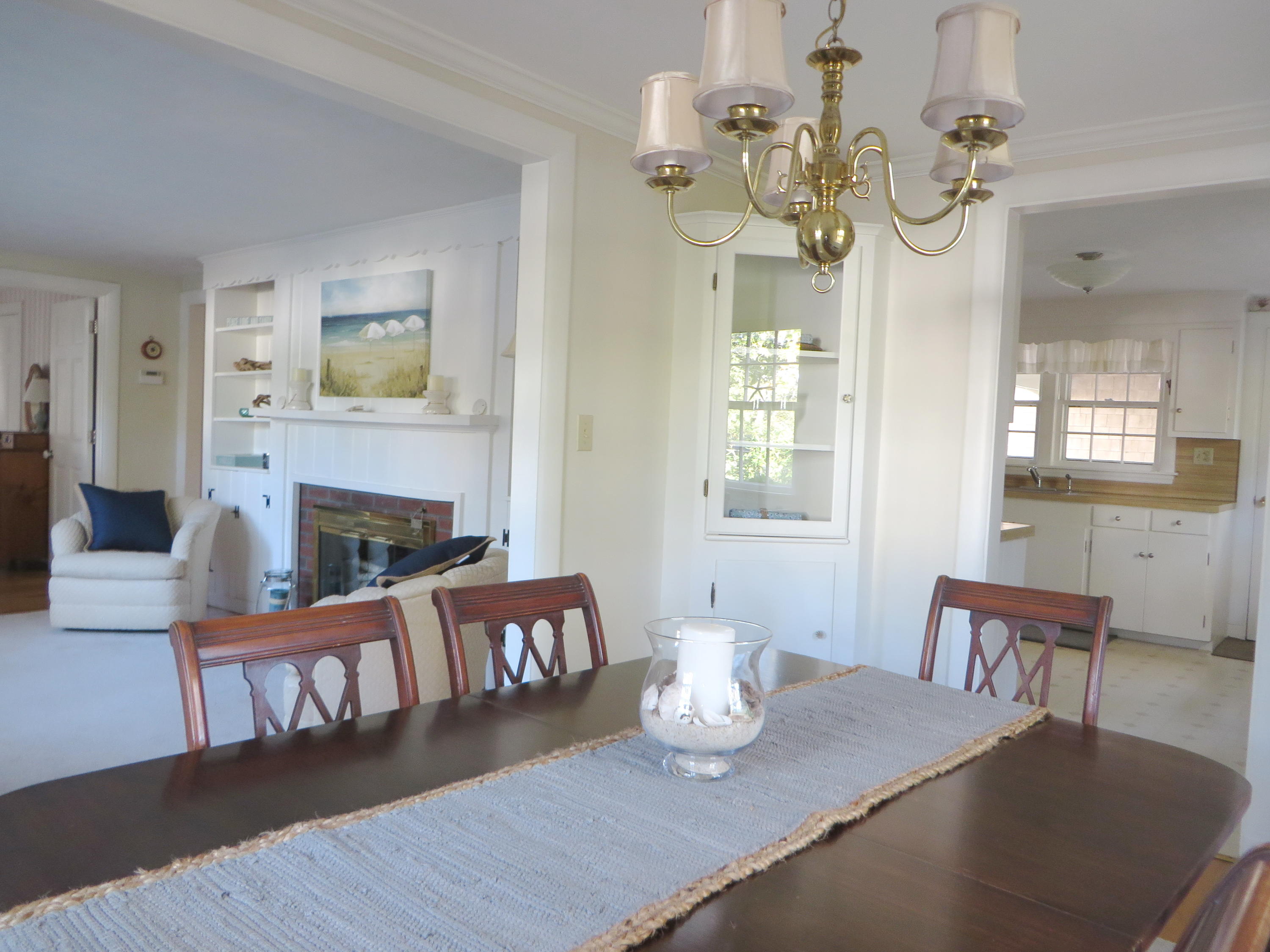 229 Lower County Road West Harwich, MA 02671 - Photo 6 of 23 a dining room with wooden floor a chandelier a wooden table and chairs