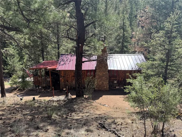 a view of a wooden house with a large window and potted plants