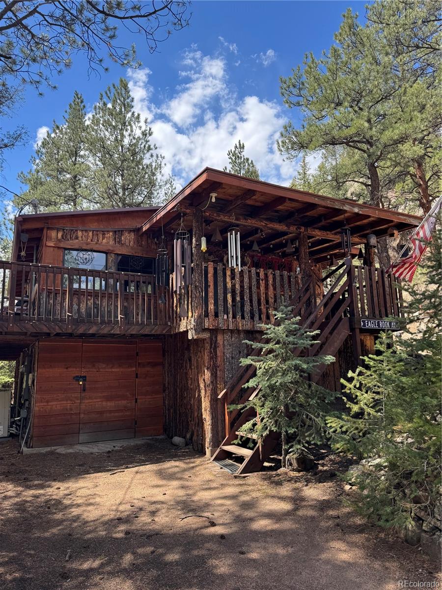 15751 South Elk Creek Road Pine, CO 80470 - Photo 5 of 34 a view of a wooden house with a large window and potted plants