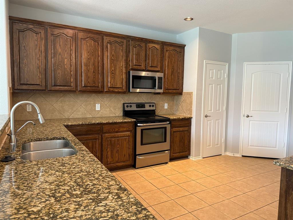 2047 Jack County Drive Forney, TX 75126 - Photo 5 of 20 a kitchen with a stove top oven a sink and dishwasher a refrigerator with wooden cabinets