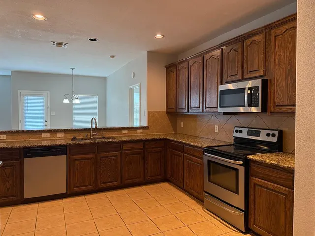 a kitchen with stainless steel appliances granite countertop a stove top oven microwave and cabinets