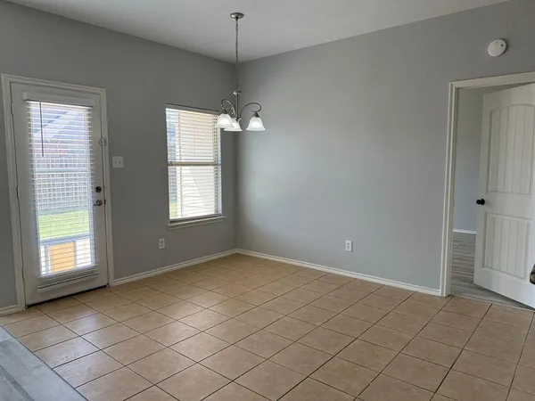 an empty room with chandelier fan and windows
