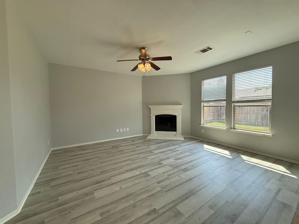 2047 Jack County Drive Forney, TX 75126 - Photo 10 of 20 an empty room with wooden floor fireplace and windows