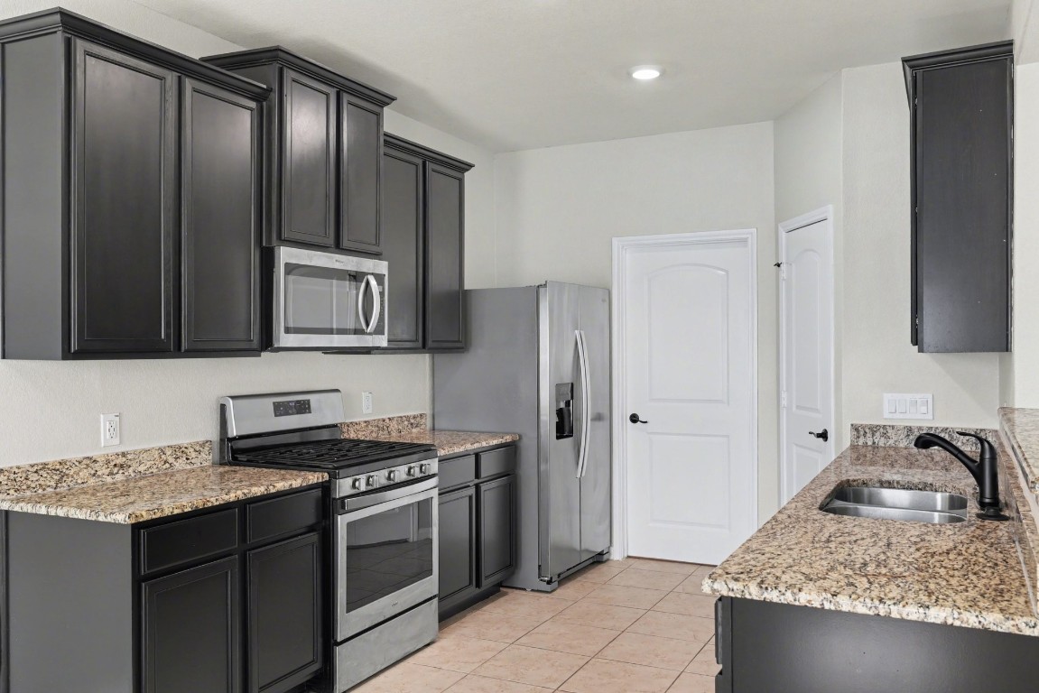 7722 Boulder Sunstone Lane Conroe, TX 77304 - Photo 12 of 25 a kitchen with granite countertop a sink stove and refrigerator