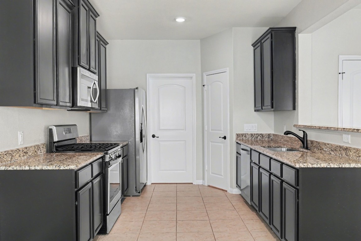 7722 Boulder Sunstone Lane Conroe, TX 77304 - Photo 13 of 25 a kitchen with stainless steel appliances granite countertop a sink stove and refrigerator