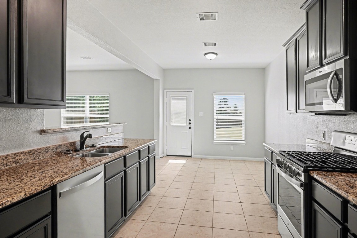 7722 Boulder Sunstone Lane Conroe, TX 77304 - Photo 14 of 25 a kitchen with stainless steel appliances granite countertop a sink stove and cabinets