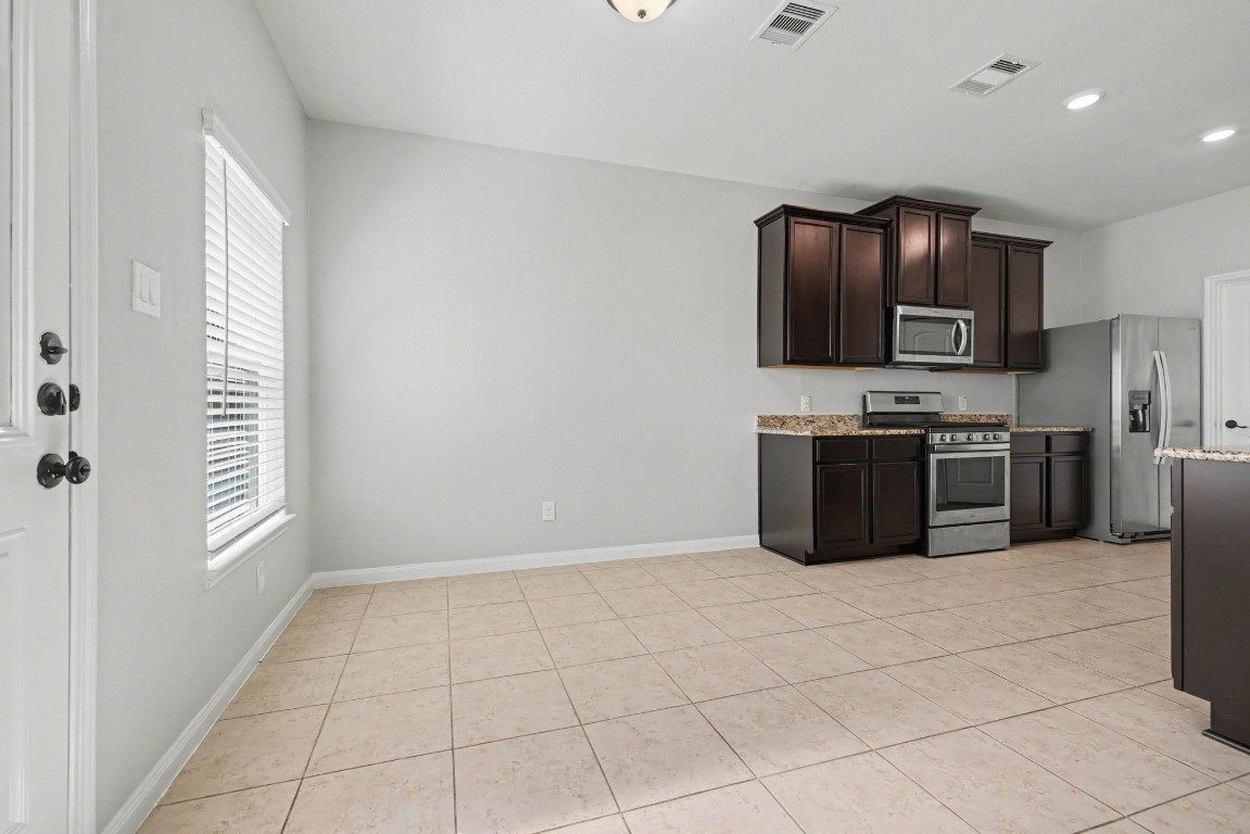 7722 Boulder Sunstone Lane Conroe, TX 77304 - Photo 10 of 25 a kitchen with stainless steel appliances granite countertop a stove top oven a sink and a refrigerator