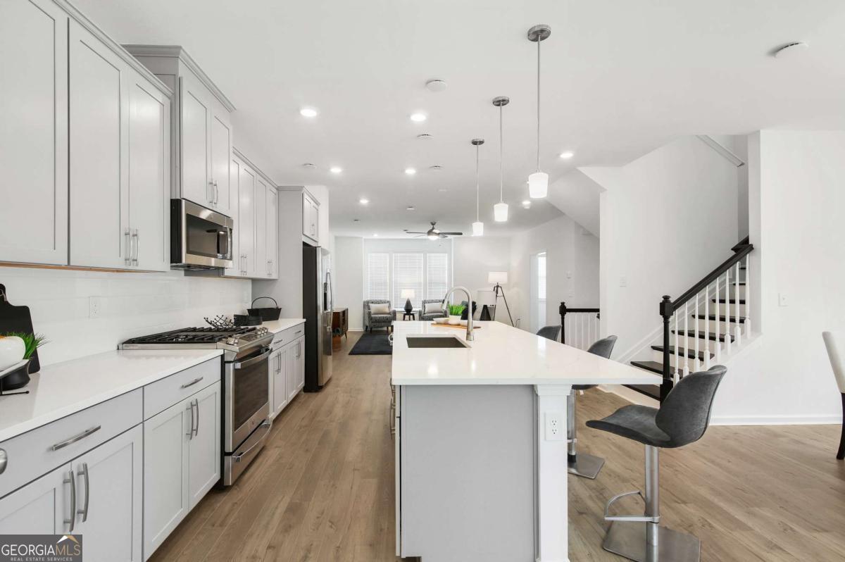 1229 Berwyn Way, Unit 1229 Suwanee, GA 30024 - Photo 4 of 21 a open kitchen with kitchen island a stove a sink a center island and wooden floor