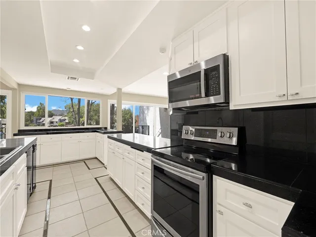 a large white kitchen with stainless steel appliances granite countertop a stove and a microwave