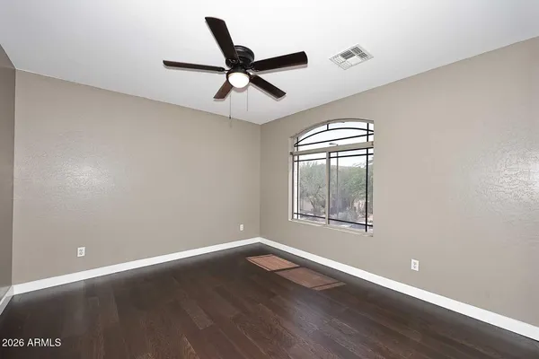 an empty room with wooden floor ceiling fan and windows