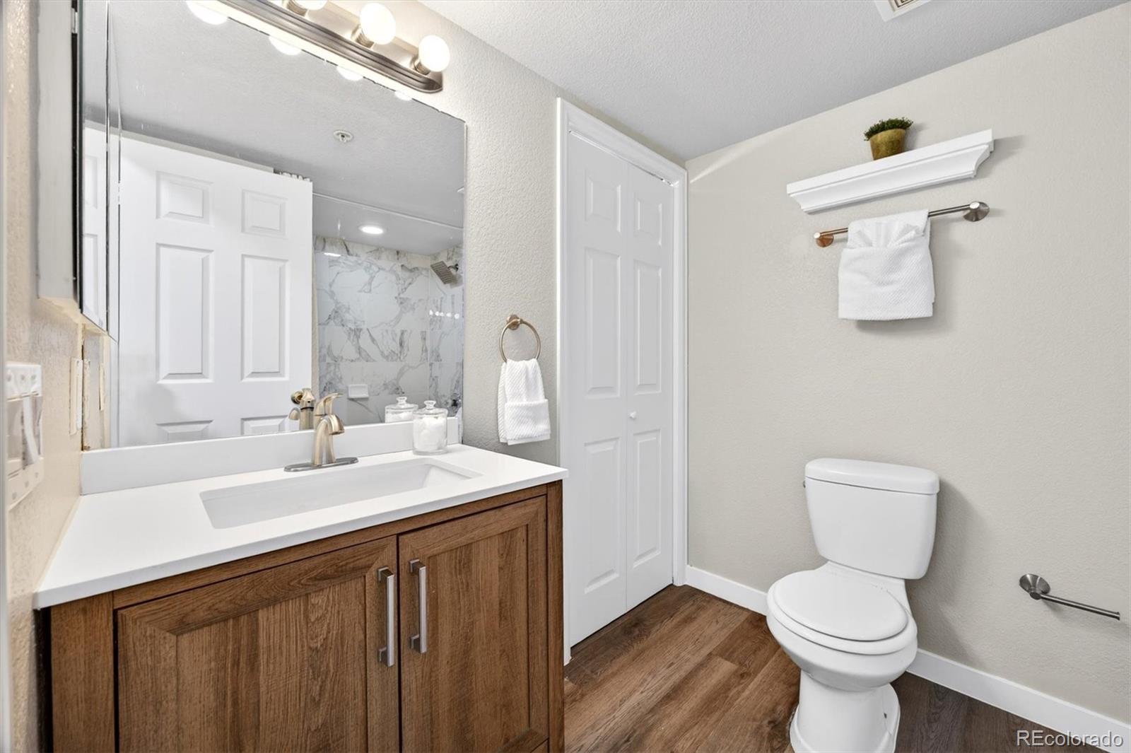 5021 Garrison Street, Unit 103A Wheat Ridge, CO 80033 - Photo 12 of 19 a bathroom with a sink a toilet and a mirror