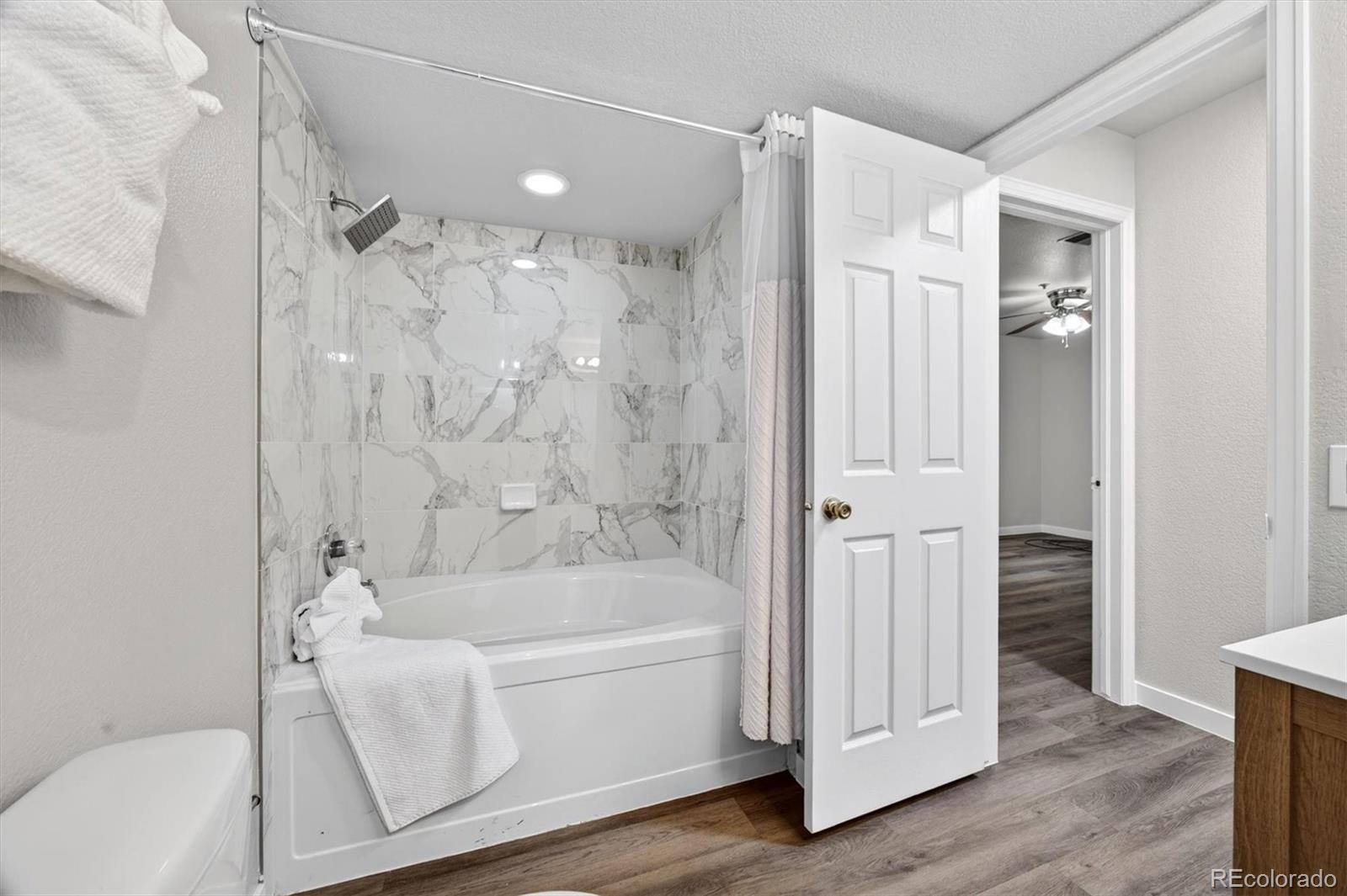 5021 Garrison Street, Unit 103A Wheat Ridge, CO 80033 - Photo 14 of 19 a bathroom with a white bath tub a mirror and a shower
