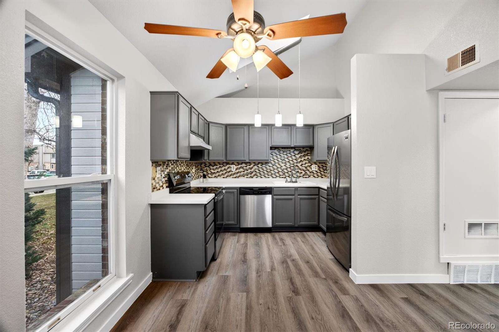 5021 Garrison Street, Unit 103A Wheat Ridge, CO 80033 - Photo 7 of 19 a large kitchen with a wooden floor and stainless steel appliances