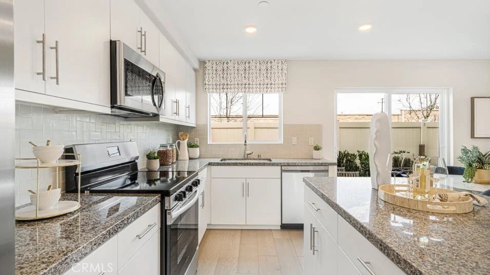 7498 Olive Grv Street Riverside, CA 92507 - Photo 2 of 14 a kitchen with stainless steel appliances granite countertop a stove a sink and a white cabinets
