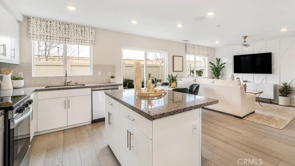 7498 Olive Grv Street Riverside, CA 92507 - Photo 3 of 14 a kitchen with granite countertop a sink and a stove top oven with wooden floor