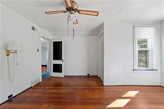 a view of an empty room with window and wooden floor