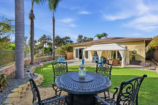 a view of a patio with table and chairs potted plants and palm tree