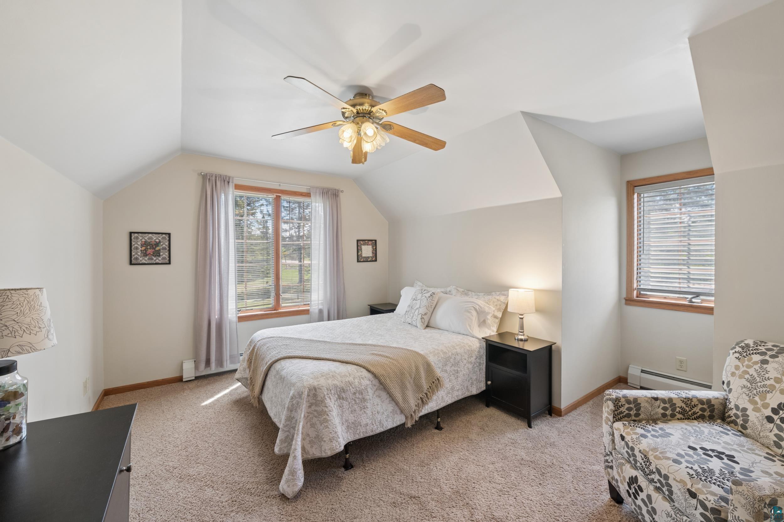 3113 Golf Course Road Ashland, WI 54806 - Photo 22 of 38 Carpeted room featuring a ceiling fan, sloped ceilings, and wood-framed windows