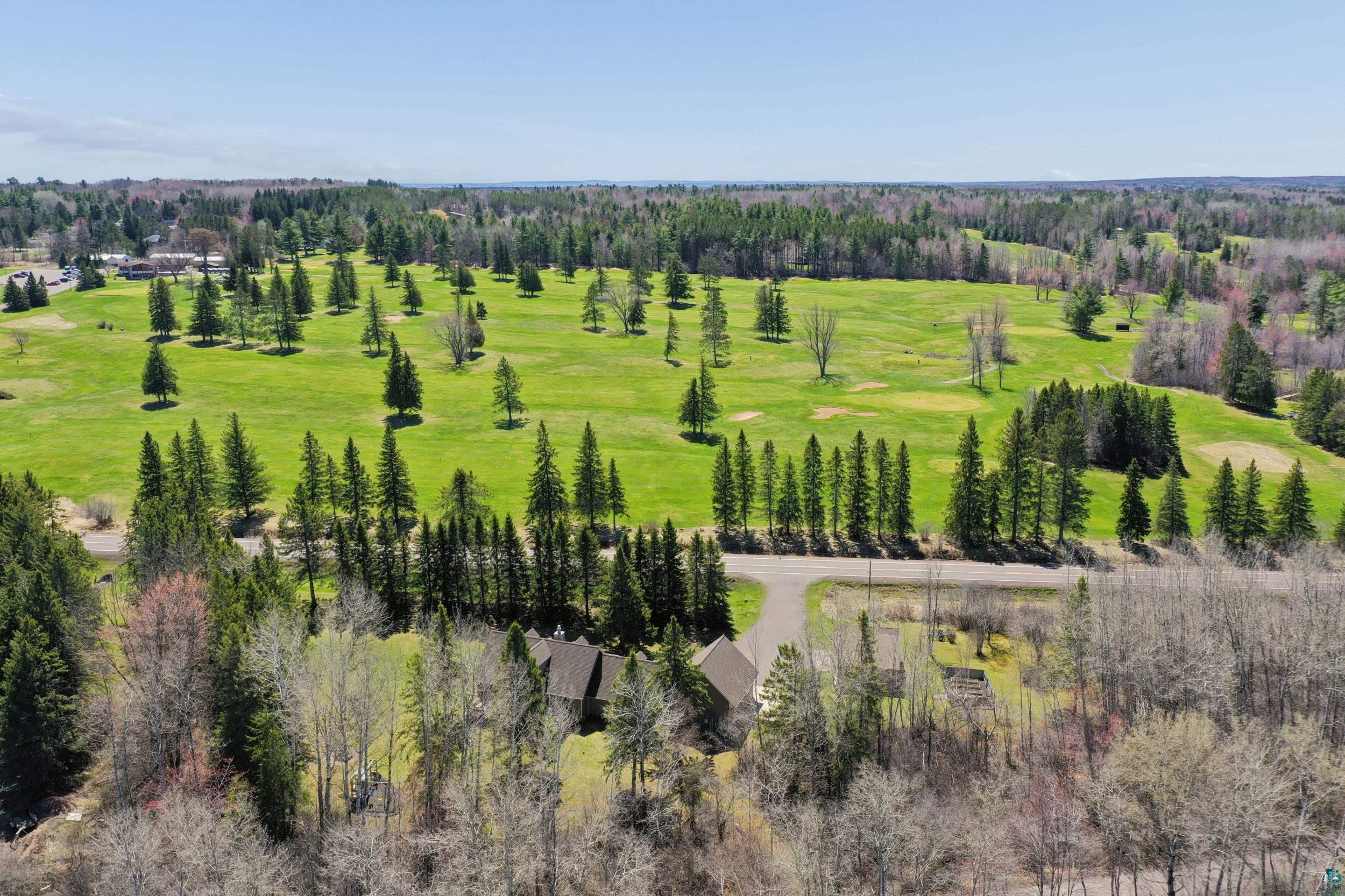 3113 Golf Course Road Ashland, WI 54806 - Photo 37 of 38 Expansive golf course landscape featuring mature evergreen and deciduous trees, with a distant residential structure partially visible
