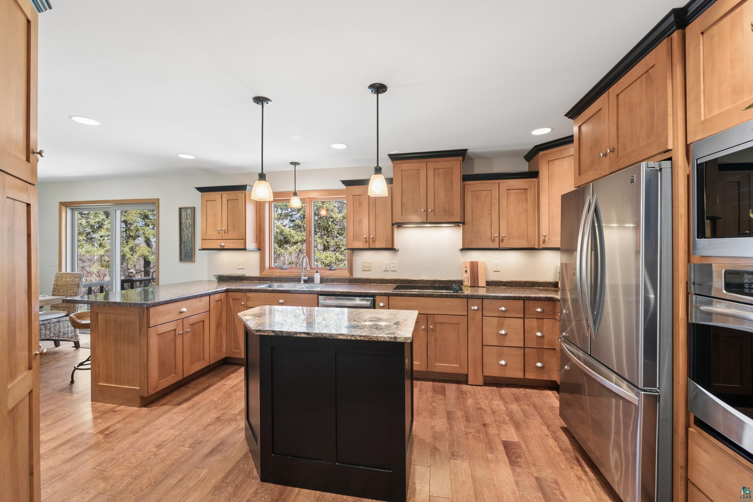 3113 Golf Course Road Ashland, WI 54806 - Photo 7 of 38 Kitchen featuring wood-finish flooring, light wood cabinetry with dark crown molding, granite countertops, and stainless steel appliances
