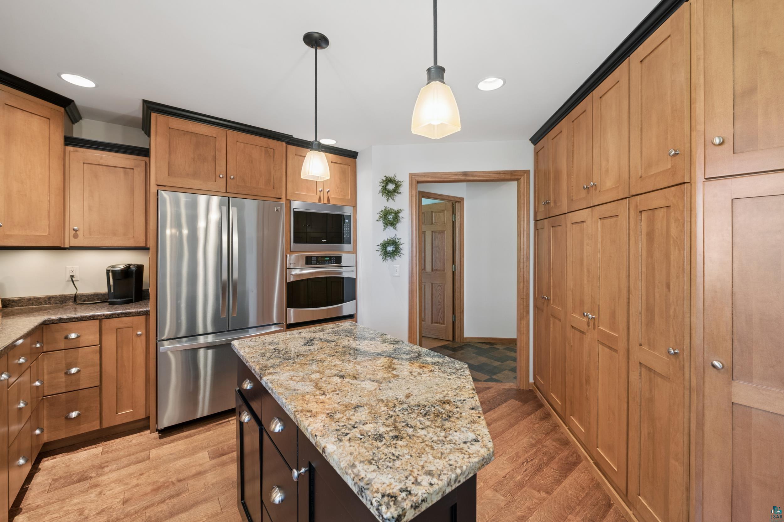 3113 Golf Course Road Ashland, WI 54806 - Photo 9 of 38 Kitchen featuring a multi-tone granite island, stainless steel appliances, extensive wood cabinetry, wood-finish flooring, and recessed lighting
