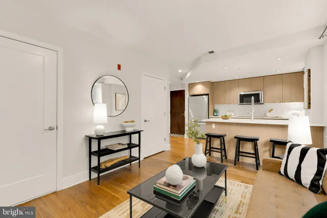 a living room with furniture a table and kitchen view
