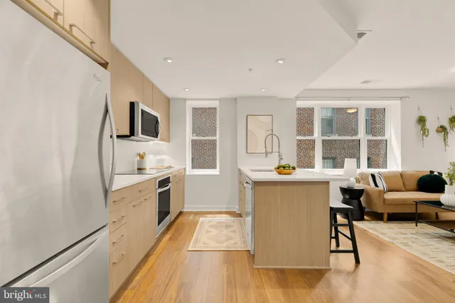 a living room with stainless steel appliances furniture and a kitchen view